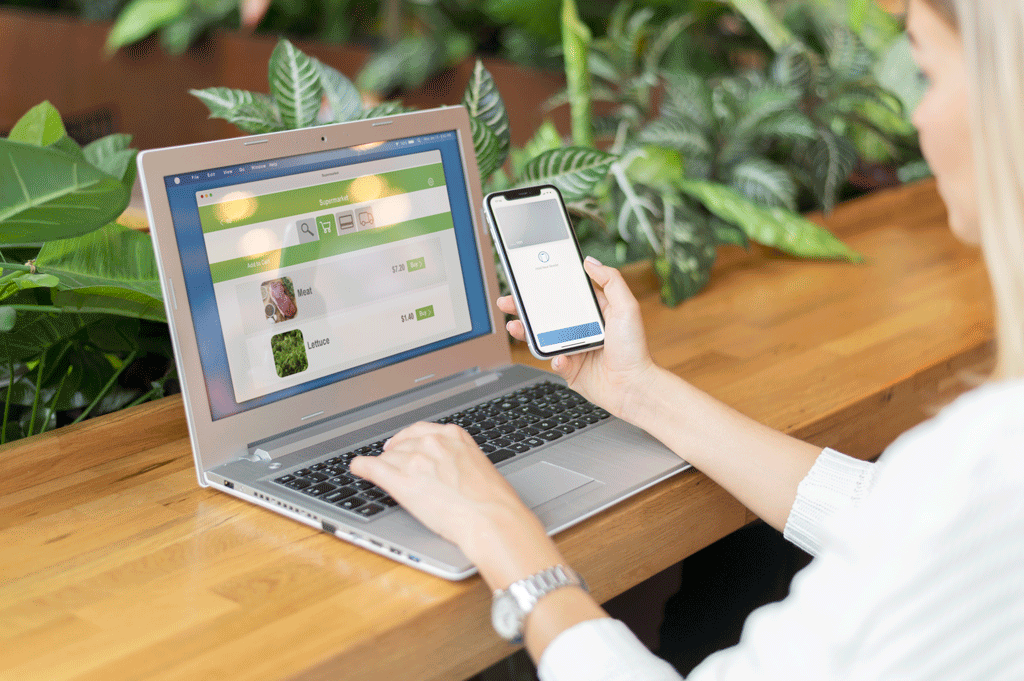 Free Laptop with open webpage on wooden desk, accompanied by tablet and pen, representing digital work setup. Stock Photo